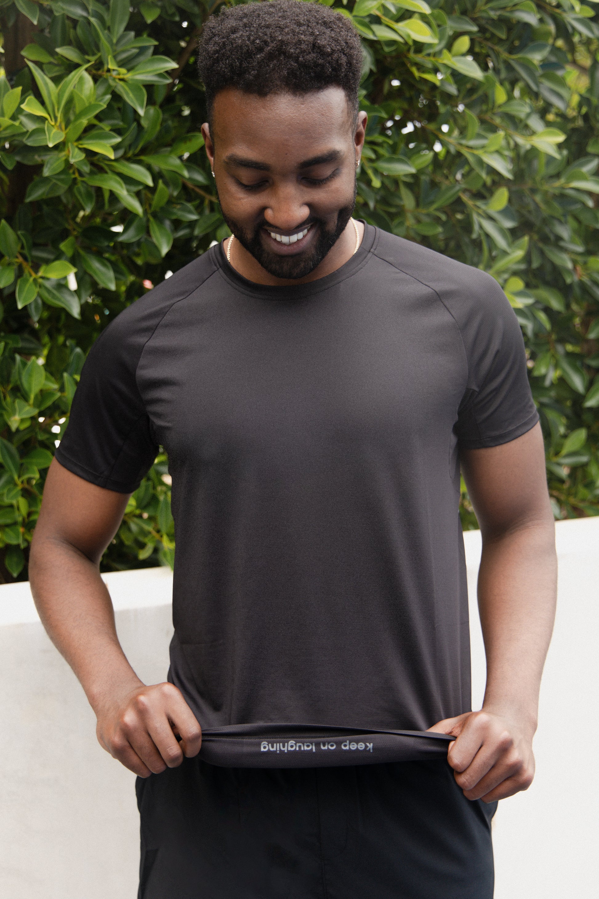 male pickleball player smiling and wearing black unlined athletic shorts and a black athletic shirt with a peekaboo logo inside the shirt